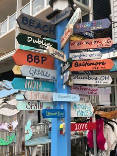 a sign post with many different colored signs on it's side in front of a building