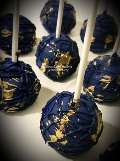 chocolate covered cake pops with gold splatkles on white sticks and blue icing