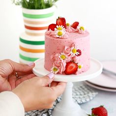 a person holding a strawberry cake with flowers on it