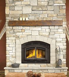 a stone fireplace with logs and candles on it