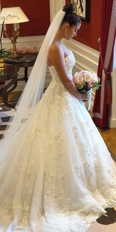 a woman in a wedding dress is looking down at her bouquet