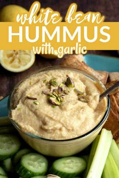 white bean hummus with garlic in a bowl surrounded by sliced cucumbers