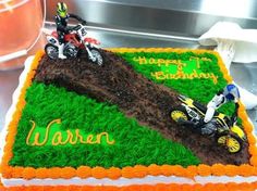 a birthday cake decorated with dirt bikes and grass