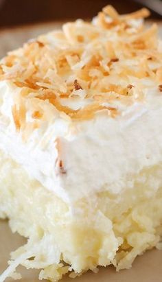 a close up of a piece of cake with white frosting and toasted coconut on top