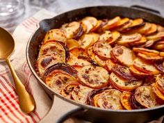 a pan filled with potatoes and onions on top of a red checkered table cloth