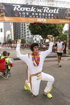 a man dressed as elvis dancing in the street at a rock'n'roll marathon