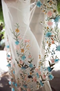 the back of a woman's dress with flowers on it and sheer white fabric