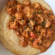 a white plate topped with rice and meat covered in gravy on top of grits