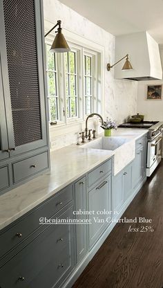 a kitchen with white marble counter tops and gray cabinetry, along with wood flooring