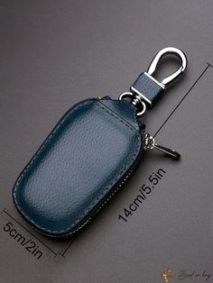 a blue leather keychain is shown on a gray surface with an identification tag attached to it