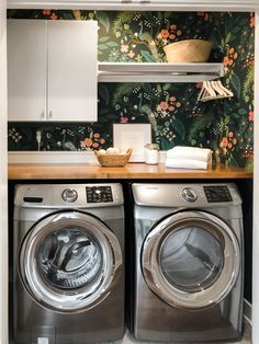 a washer and dryer in a small room with floral wallpaper on the walls