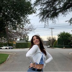 a woman standing in the middle of a street with her hands on her hips and looking at the camera