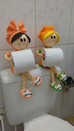 two cartoon figures sitting on top of a toilet in a bathroom with paper towels and slippers