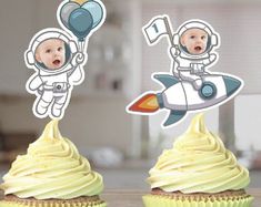 two cupcakes with stickers on top of them that look like astronauts in space