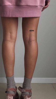 the legs and ankles of a woman with tattoos on her left leg, wearing pink shoes