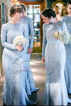 two women in blue dresses standing next to each other and one is holding a bouquet