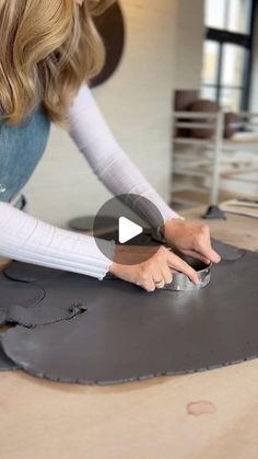 a woman is working on a piece of leather with a video screen showing how to use it