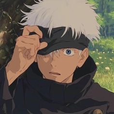 a man with white hair and blue eyes wearing a blindfold in front of a tree