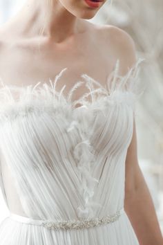 a woman wearing a white dress with feathers on it