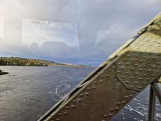 the view from inside a boat looking out at water and houses on land in the distance