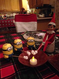 an elf is making minion candles on the table in front of some minions