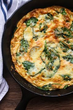 an omelet with spinach and cheese in a cast iron skillet on a wooden table