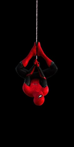 a spider man hanging upside down in the dark