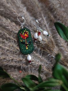 a pair of earrings with beaded designs and pearls hanging from the earwires