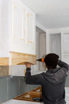 a man is working on the cabinets in his kitchen, with wood being put together