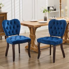 two blue chairs sitting in front of a wooden table