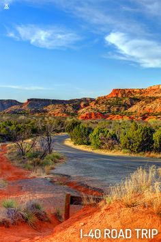 an empty road in the desert with trees and bushes on either side that is surrounded by red rock formations