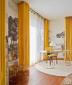 a room with yellow drapes and curtains on the windowsills is furnished with a round dining table surrounded by yellow chairs