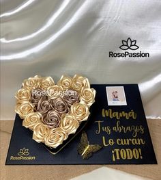 a heart shaped box filled with roses on top of a table next to a card