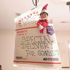 an elf hanging from the ceiling holding a special delivery sign