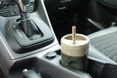 a cup that is sitting in the center console of a car with a wooden stick sticking out of it