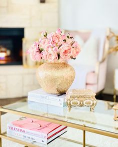 a glass table topped with books and a vase filled with pink flowers