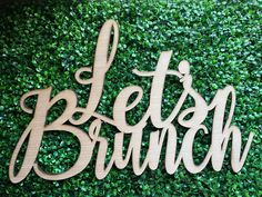 a wooden sign that says, let's brunch on top of a green wall