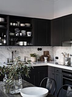 a kitchen filled with lots of black cabinets and counter top space next to a wooden table