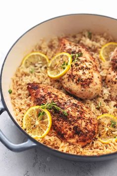 chicken and rice in a pan with lemons on the side for garnish