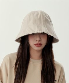 a woman wearing a white hat with long dark hair and brown eyes is looking at the camera