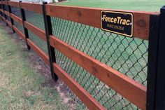 a fence that has a sign on it and some grass in the back ground behind it