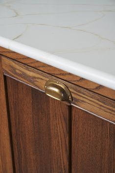 a wooden cabinet with marble top and brass pulls on the door handle is seen in this image