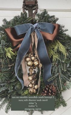 a wreath with a blue ribbon and some pine cones hanging from it's side