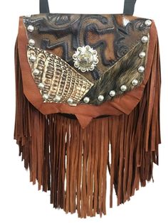 Handmade of velvety soft brown deerskin with a 7" brown deerskin fringe. The flap features genuine alligator, hair-on-hide and printed leather. The centerpiece is a striking silver concho. Etched silver metal studs trim the outline of the bag. Wear bag clipped to belt loops for hands-free carrying of your essentials. Interior includes a leather strap. Add the strap when you want a completely different look. Unique Brown Bag For Everyday Use, Hand Tooled Brown Bag, Unique Hand Tooled Brown Bag, Unique Hand-tooled Brown Bag, Unique Hand-stitched Bags For Everyday Use, Artisan Brown Bag With Leather Backing, Hand Tooled Leather Bag, Fur Bags, Animal Hide