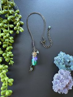 Handmade mushroom potion, carved rainbow moonstone leaf, and a faceted labradorite moon all hang together on a short gunmetal chain. A few round amethyst beads adorn the chain, finished with a lobster claw clasp, 2" extension, and a green strawberry quartz drop. Adjustable length, 16-18" long. Potion is made using UV resin.  Potion bottle is glass, please handle with care. Chain is non-tarnish gunmetal plated brass. May not be suitable for those with allergies. Mushroom Potion, Moon Potion, Potion Bottle Necklace, Potion Necklace, Witch Necklace, Green Strawberry, Bottle Necklace, Potion Bottle, Necklace Crystal