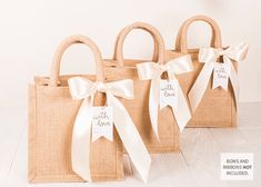 three burlap bags with white ribbons tied around the handles and tags on them