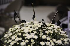 white flowers with musical notes on them are in the center of a table top arrangement