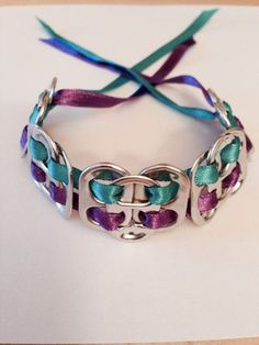 the bracelet is decorated with purple, green and blue ribbons on a white tablecloth