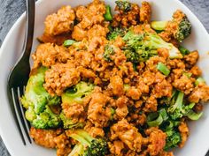 a white bowl filled with meat and broccoli on top of a gray table