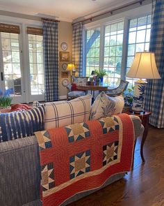 a living room filled with furniture and windows covered in blue and white quilts on the couches